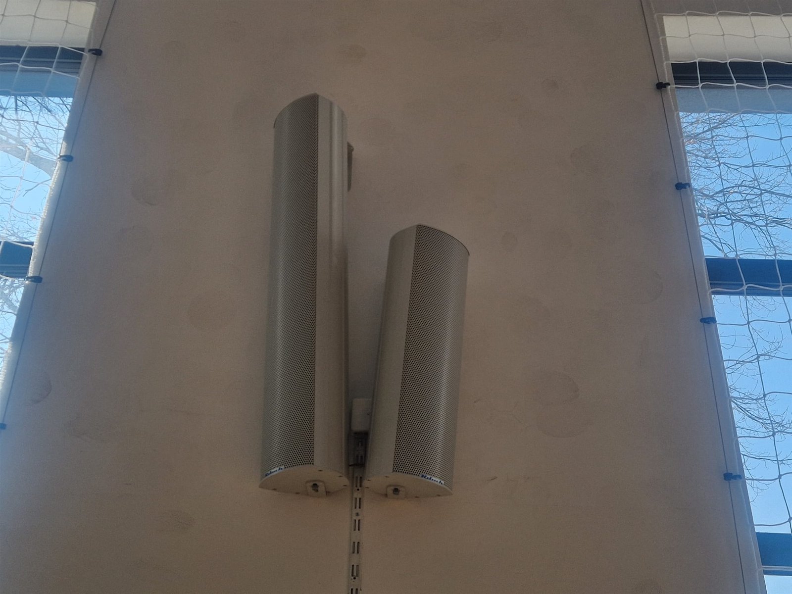 Zestaw głośników instalacyjnych zamontowanych na ścianie hali